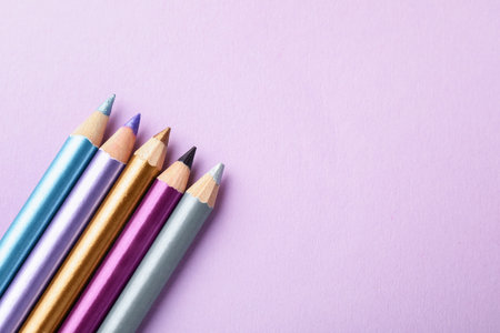 Eye pencils on lilac background, flat lay. Space for textの写真素材