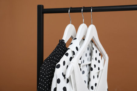 Different clothes hanging on rack against brown background, closeupの写真素材