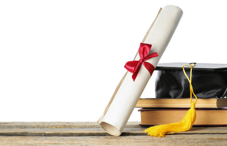 Diploma, books and graduation hat on wooden table against white backgroundの写真素材