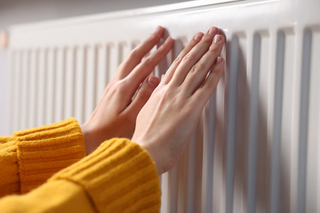 Woman warming her hands near radiator indoors, closeupの写真素材
