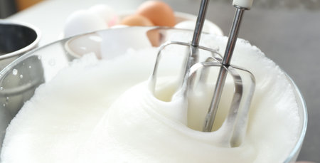 Beating egg whites with mixer at gray table, closeupの写真素材