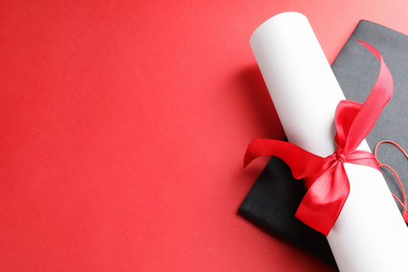 Diploma and graduation hat on red background, above view. Space for textの写真素材