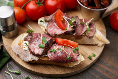 Delicious bruschettas with roast beef served on wooden table, closeupの写真素材