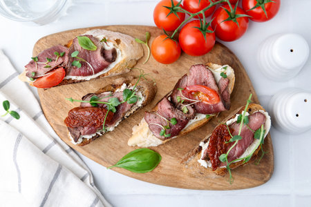 Delicious bruschettas with roast beef served on white table, flat layの写真素材