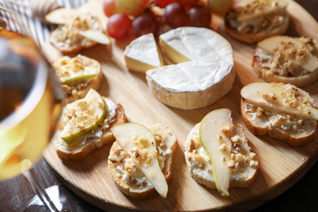 Delicious bruschettas served with camembert and grapes on wooden table, closeupの写真素材