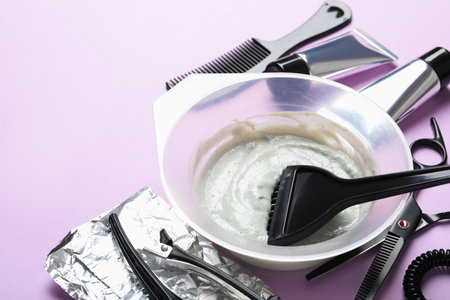 Professional tools and products for hair dyeing on violet background, closeup. Space for textの写真素材