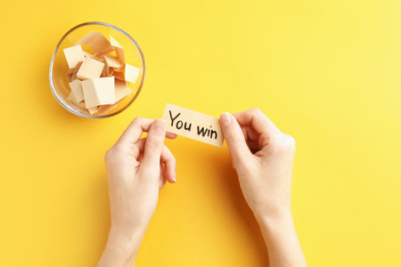 Woman holding note with text You Win and paper pieces on yellow background, top viewの写真素材