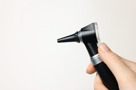 Hearing test. Woman with otoscope on light background, closeup. Space for textの写真素材