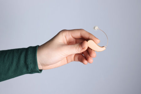 Woman with hearing aid on light gray background, closeupの写真素材