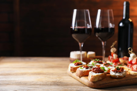 Different delicious bruschettas and red wine on wooden table. Space for textの写真素材