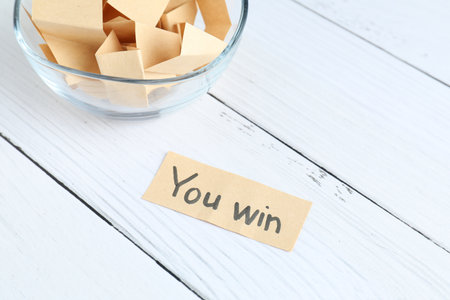 Note with text You Win and paper pieces on white wooden table, closeupの写真素材