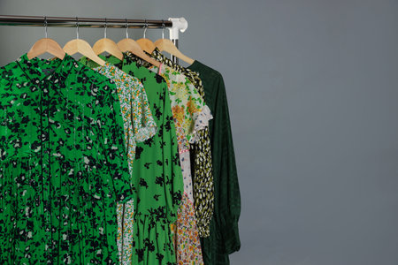 Different stylish clothes hanging on rack against gray background, closeup. Space for textの写真素材