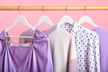 Different clothes hanging on rack against pink background, closeupの写真素材
