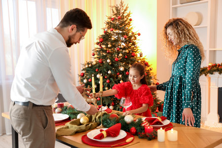 Happy family setting table in room decorated for Christmasの写真素材