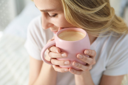 Woman with cup of cocoa drink on bed at home, closeupの写真素材