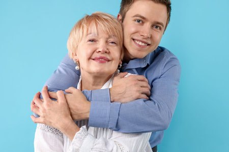 Son hugging his mother on light blue background