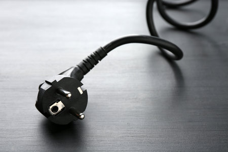 Electrical wire with plug on black wooden table, closeupの写真素材