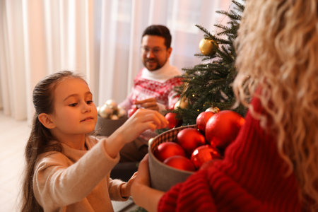 Happy family decorating Christmas tree together at home, selective focusの写真素材
