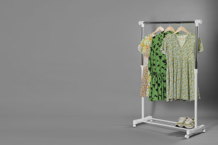 Different stylish clothes and shoes on rack against gray background, space for textの写真素材