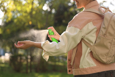 Woman spraying tick repellent onto hand in park, closeupの写真素材