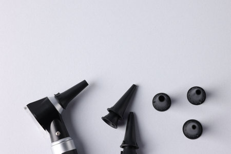 Hearing test. Modern otoscope and ear speculums on light gray background, flat lay. Space for textの写真素材