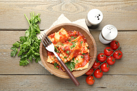 Delicious ravioli with tomato sauce and parsley served on wooden table, flat layの写真素材
