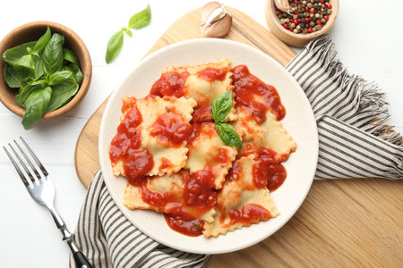 Delicious ravioli with tomato sauce and basil served on white wooden table, flat layの写真素材