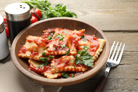 Delicious ravioli with tomato sauce and parsley served on wooden table, closeupの写真素材