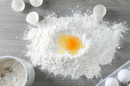Broken eggs, yolk and flour on wooden table, flat layの写真素材