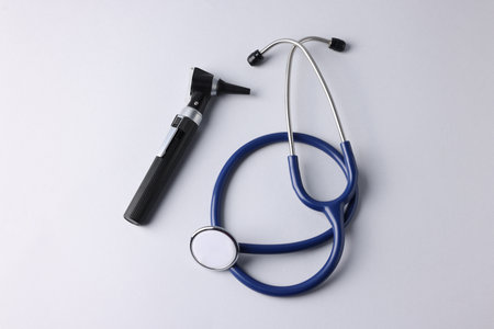 Hearing test. Modern otoscope and stethoscope on light gray background, flat layの写真素材