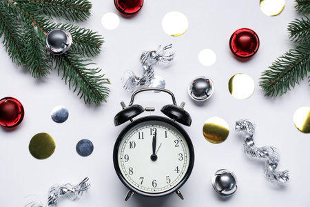 New Year celebration. Alarm clock and festive decor on light gray background, flat lay