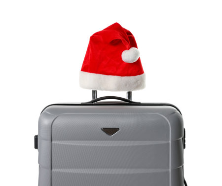 Stylish gray suitcase with Santa hat isolated on white. Christmas vacationの写真素材