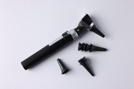 Hearing test. Modern otoscope and ear speculums on light gray background, flat layの写真素材