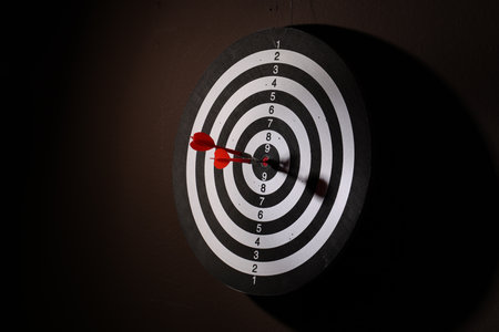 Dartboard with darts on black background, closeup. Space for textの写真素材