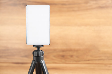 LED lamp on tripod against wooden background, closeup. Space for textの写真素材