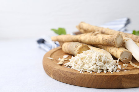 Whole and grated horseradish roots on light gray table, closeup. Space for textの写真素材