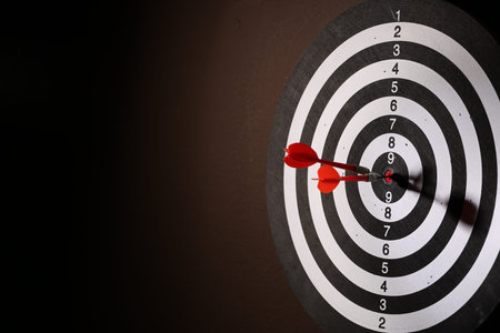 Dartboard with darts on black background, closeup. Space for text