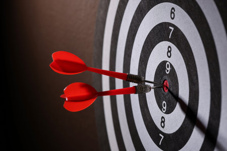 Dartboard with darts on black background, closeup