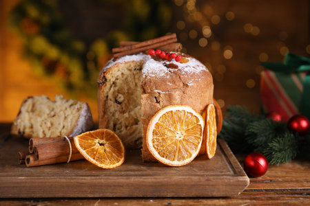 Christmas food. Delicious Panettone cake and festive decor on wooden table against background with blurred lights, closeupの写真素材