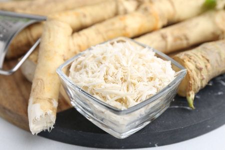 Whole and grater horseradish roots and grater on white table, closeupの写真素材