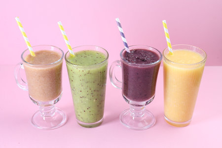 Different tasty smoothies in glasses on pink backgroundの写真素材