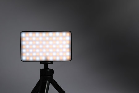 Stylish LED lamp on tripod against gray background, closeup. Space for textの写真素材