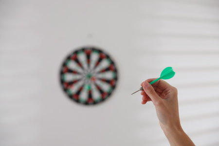 Woman with dart aiming at dartboard indoors, selective focusの写真素材