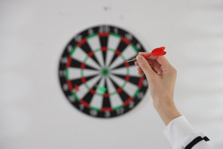 Woman with dart aiming at dartboard indoors, selective focusの写真素材