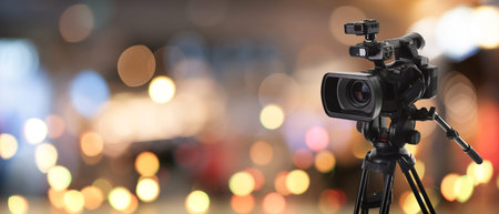 Video camera on stand against blurred background with bokeh lights. Banner design