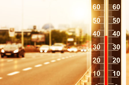 Thermometer showing high temperature, double exposure with road in city during hot dayの写真素材