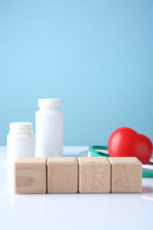 Stethoscope, pills, heart figure and blank wooden cubes on white table against light blue background. Mockup for designの写真素材