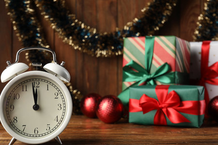 Alarm clock, tinsel, baubles and gift boxes on wooden table, closeup. New Year greeting cardの写真素材