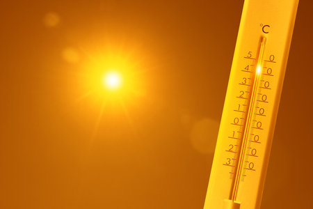 Thermometer with high temperature against orange sky with bright sun. Extremely hot weatherの写真素材