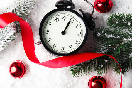 Alarm clock and festive decor on artificial snow, flat lay. New Year greeting card